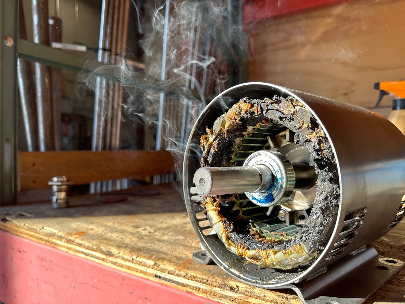 A burned-out electric motor stator smoking on the workbench