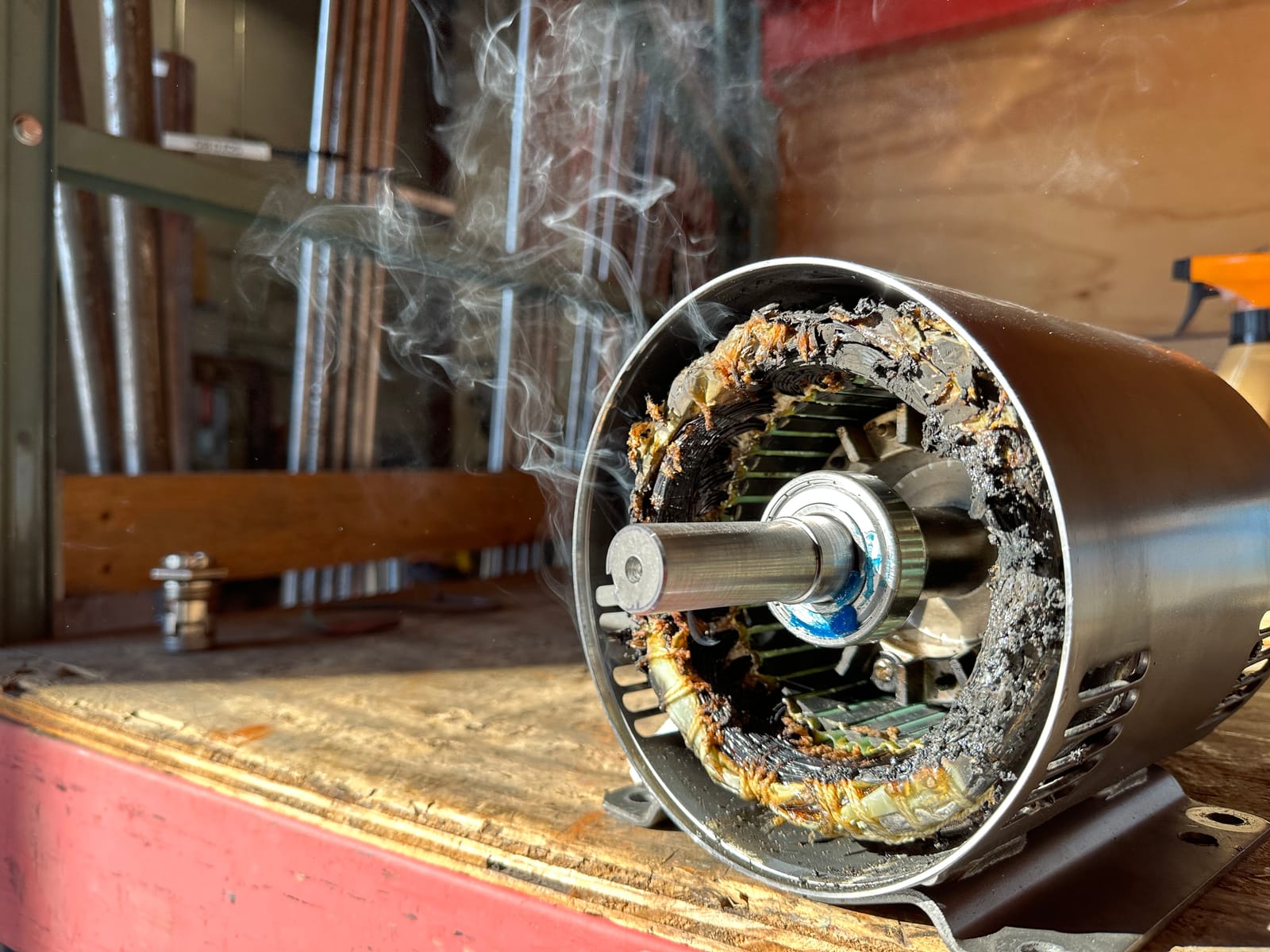 A burned-out electric motor stator smoking on the workbench